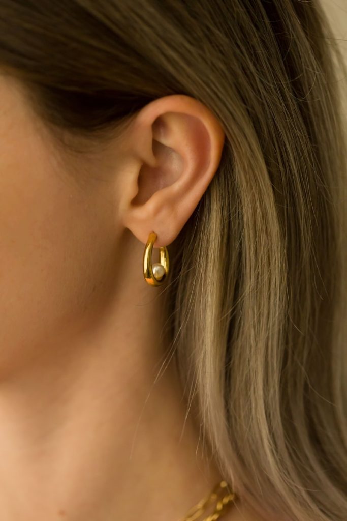 gros plan d'une personne portant une paire de boucles d'oreilles